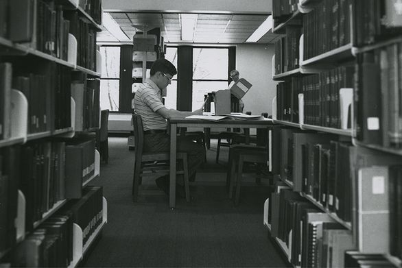 Man looking through archival box in library.