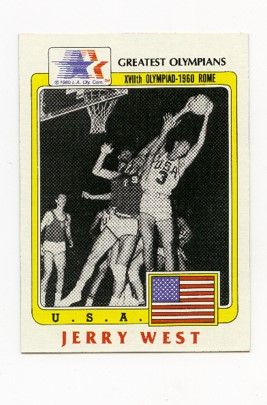 A small card-sized image of Jerry West mid-game. The top reads "Greatest Olympians." A yellow frame with rounded edges surrounds the photo, and on the bottom are the words "USA" and an american flag. beneath, the name "Jerry West"