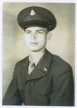 The same young man, a little older, a little thinner, wears a military jacket and hat, over a shirt and tie. He looks thoughtfully past the camera.