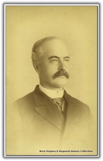 a picture of a man with balding gray hair and a large mustache. he looks off center and is wearing a jacket over a cravat and a high necked white shirt