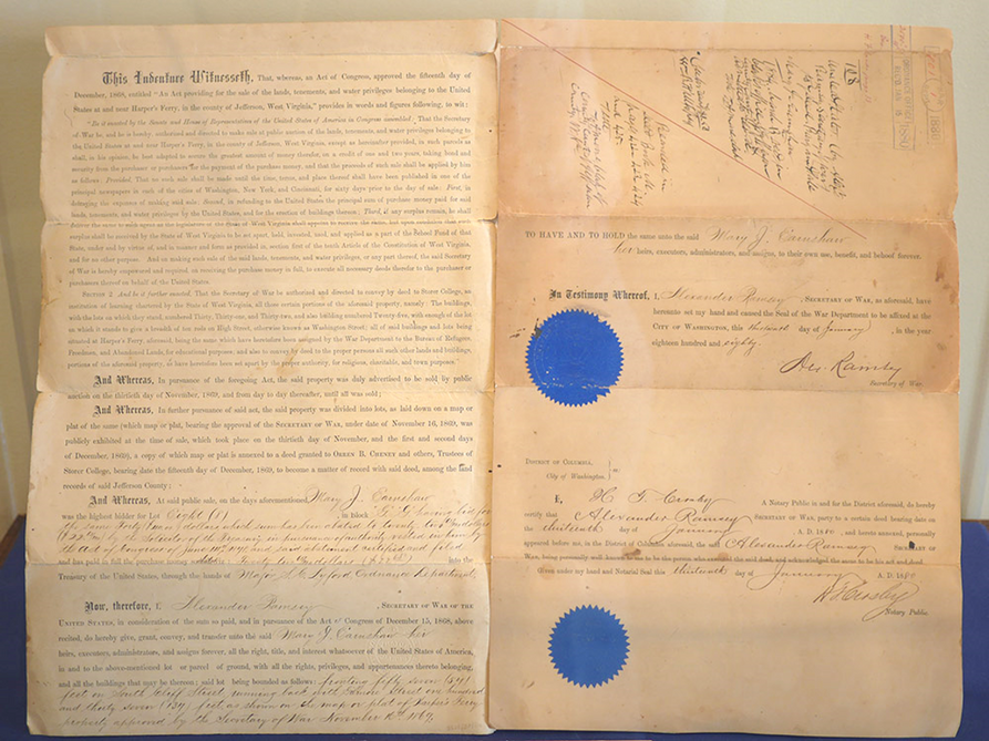 The deed to Storer College. It is a two-page spread, the pages yellowed, with two bright blue seals stuck on the righthand page