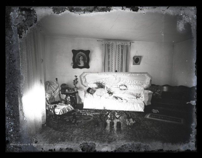 a black and white photo of a small coffin displayed in a sitting room