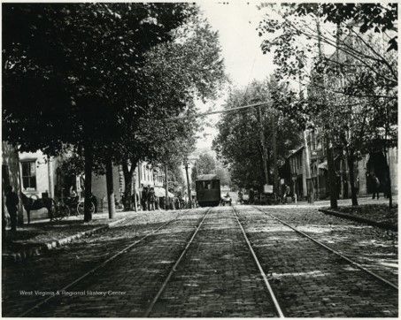 Black and white image of a trolley track, with a trolley in the distance