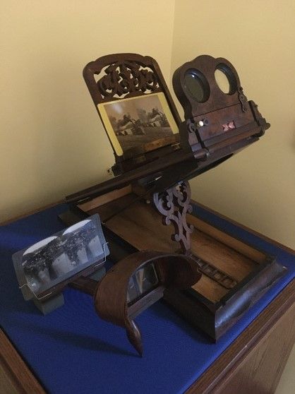 A displayed stereoscope, set up for viewing. Displayed on a blue pedestal. 