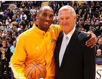 Kobe Bryant and Jerry West pose together on the court. Kobe wears a bright yellow training jacket and holds a basketball. Jerry is elderly and wears a black suit. Kobe is smiling and both look into the camera