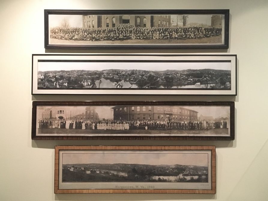 Four framed panoramic photos of town and landscapes, hung on a cream colored wall. 