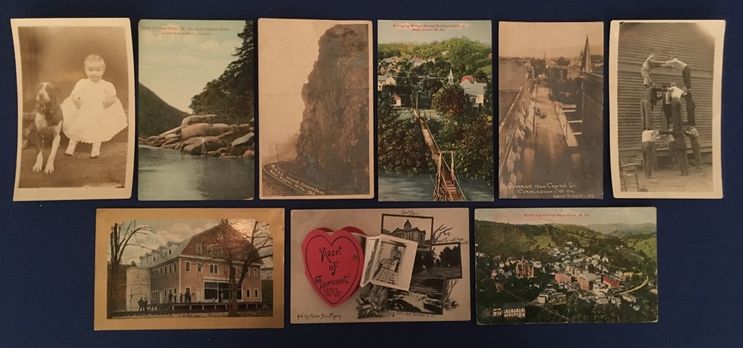 A selection of 9 postcards: a toddler with a dog, several rivers and landscapes, an aerial view of a town, a valentines day image and a large building.