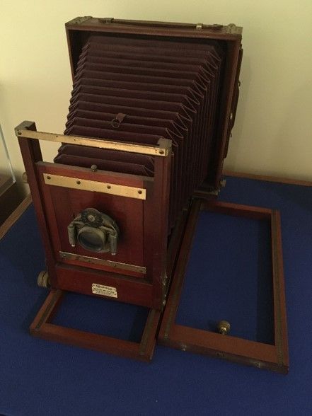 A studio camera from the early 1900s made of mahogany wood, with a cherry base and brass hardware. 