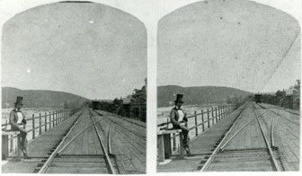 A stereograph slide of railroad tracks with a person standing on the left