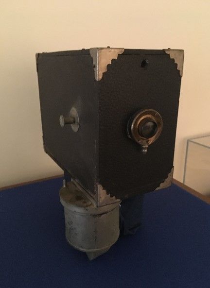 An image of a tintype camera, a large black box with a round lens on one side. 