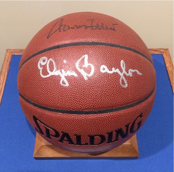 A spalding basketball signed by Elgin Baylor displayed on a blue background