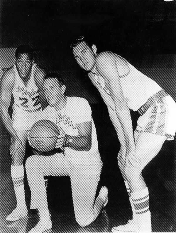 fred schaus crouched between Jerry west on the right and Elgin Baylor 