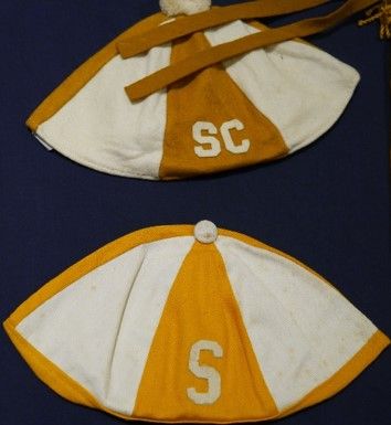 Two Storer College studen beanies, gold and white alternating panels with "SC" on the top one and "S" on the bottom one.