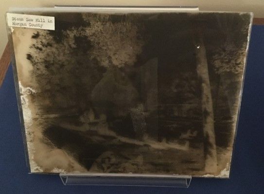 glass plate negative of the outdoors, showing trees and a saw mill 