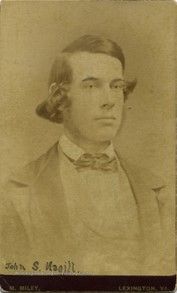A young man with medium length dark hair, parted to the side and styled neatly. He wears a bowtie, white shirt and jacket. He has a long, narrow face and looks thoughtful.