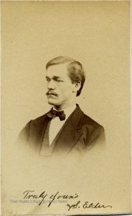 An image of a man with a mustache and a necktie looking to the side. 