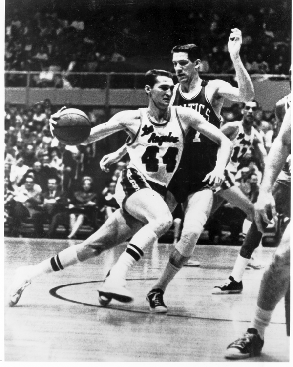 Jerry West lunges forward mid-game, the ball in his hand, and powers past the Celtics defender, John Havliceck, a white man with brown hair