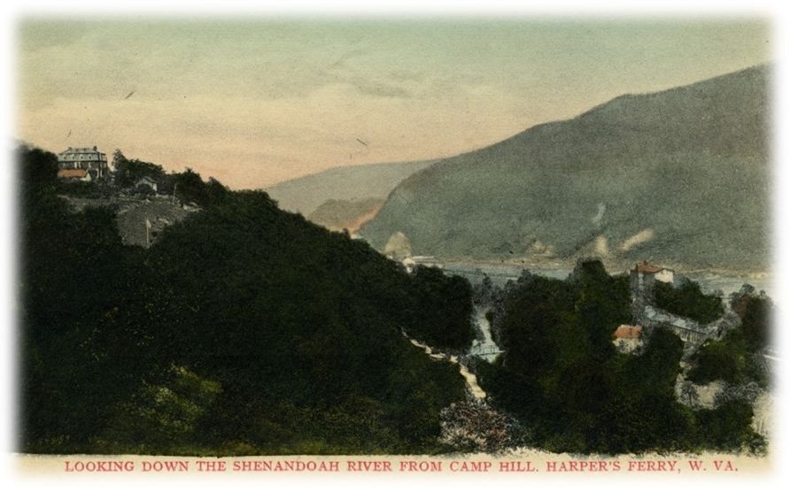 The Shenandoah river from a high view. The river snakes between two mountains covered in trees. On the mountain to the left is the Lockwood house. On the right, in the valley are several buildings. 