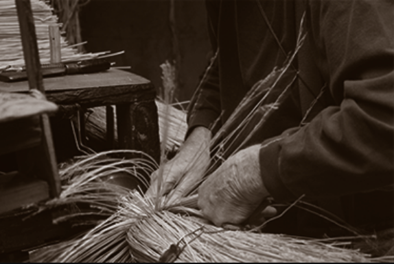 hands crafting straw broom