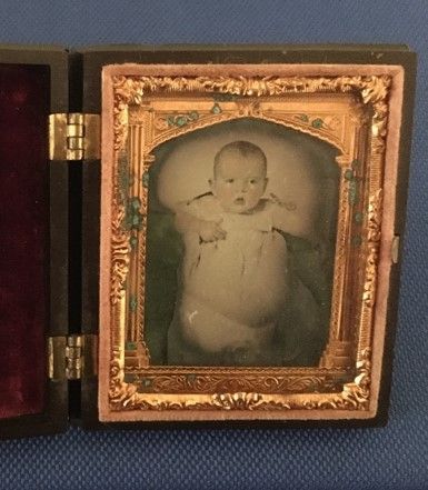 A photo of a baby, framed by an ornate golden frame