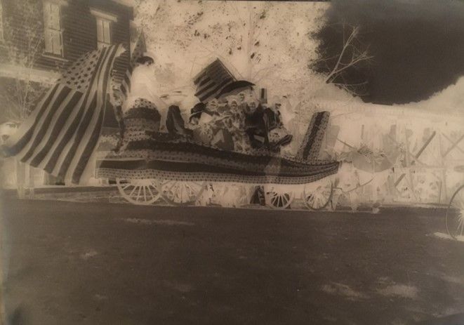A glass plate negative of a wheeled cart with an American flag on display