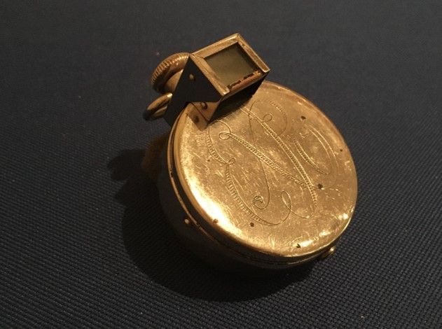 A small gold circular object shaped like a pocket watch. 