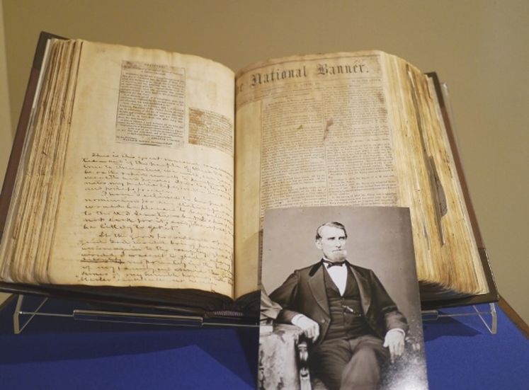 An open diary that belonged to Waitman Willey, displayed on a blue surface, with Willey's photograph in front. 