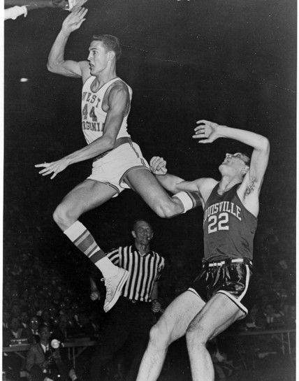 Jerry West jumps into the air to score a point, he is mid-air and the opposing team's player falls back behind him